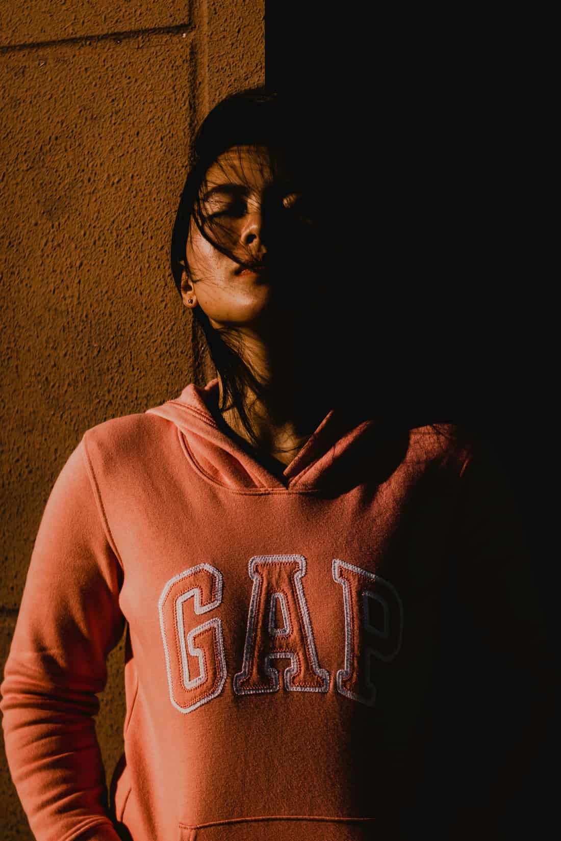 Pessoa usando moletom com a marca Gap estampada, em ambiente com luz alaranjada