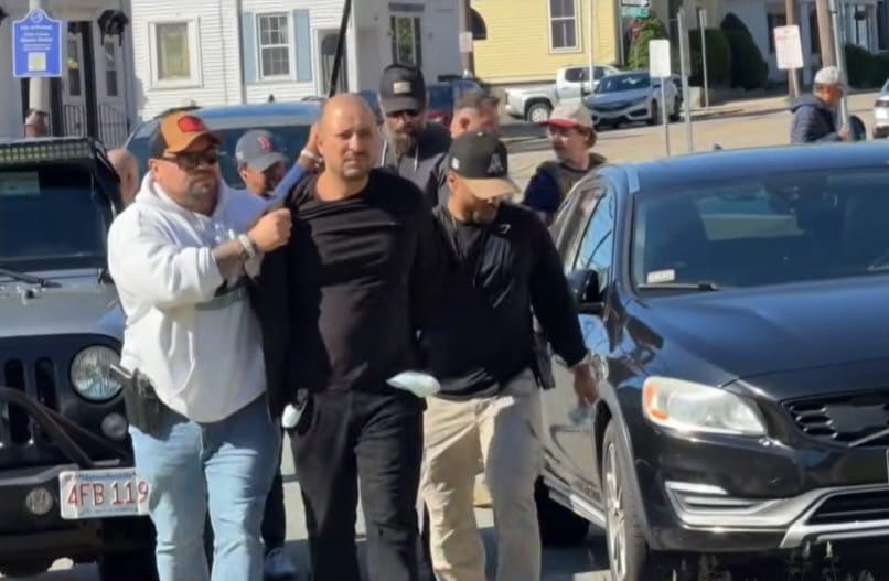 Agentes à paisana conduzem um homem algemado em frente a um tribunal