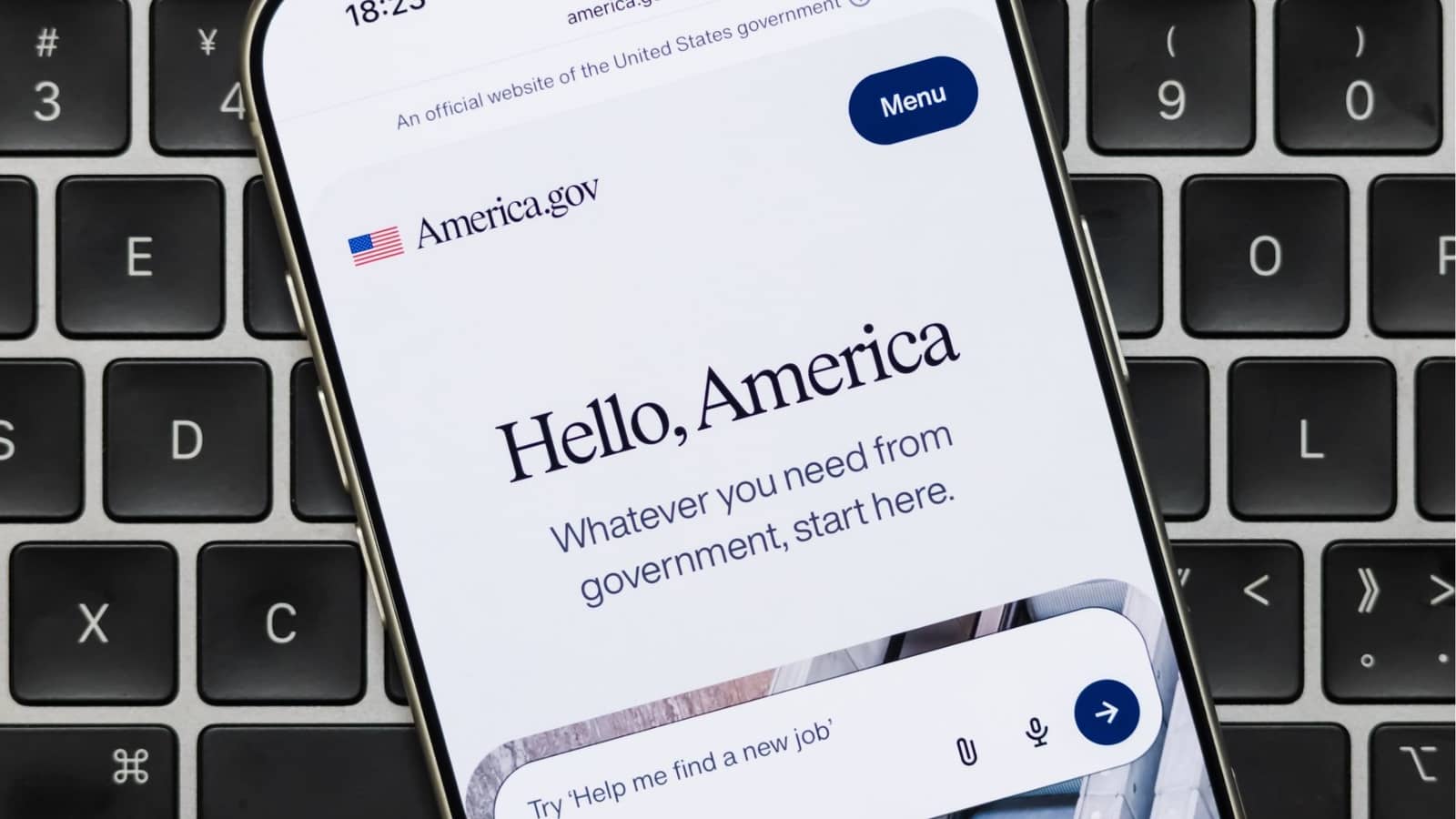 Celular exibe a página inicial do America.gov, com a mensagem Hello, America, sobre um teclado de computador