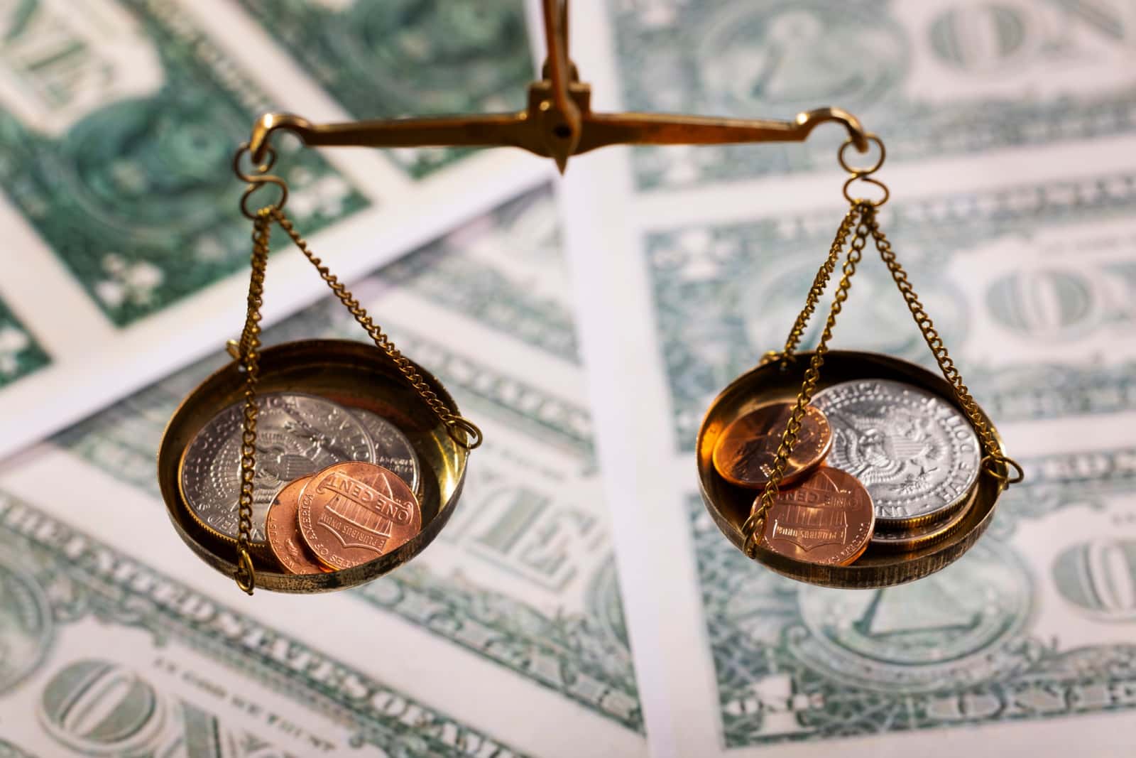 Balança de precisão equilibrando moedas americanas sobre notas de dólar