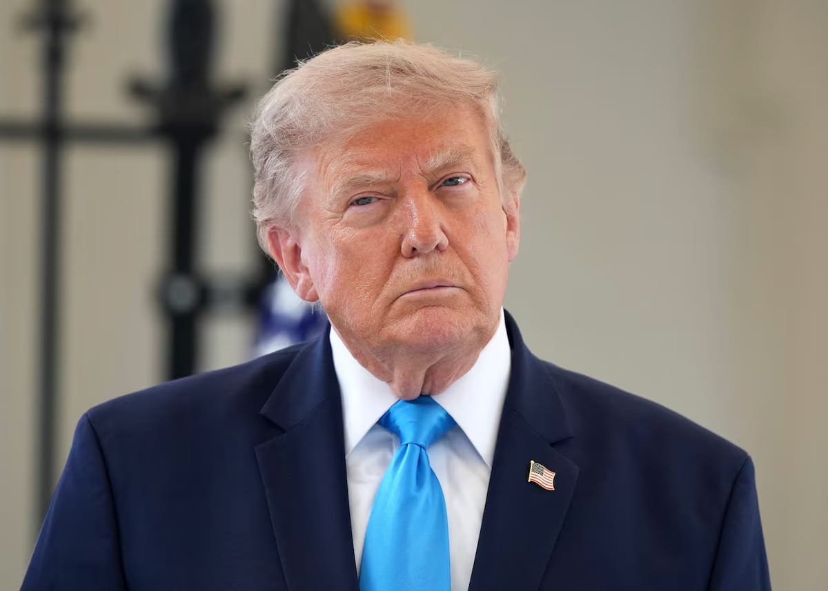 Donald Trump, de terno azul-marinho e gravata azul-clara, com expressão séria, ao ar livre