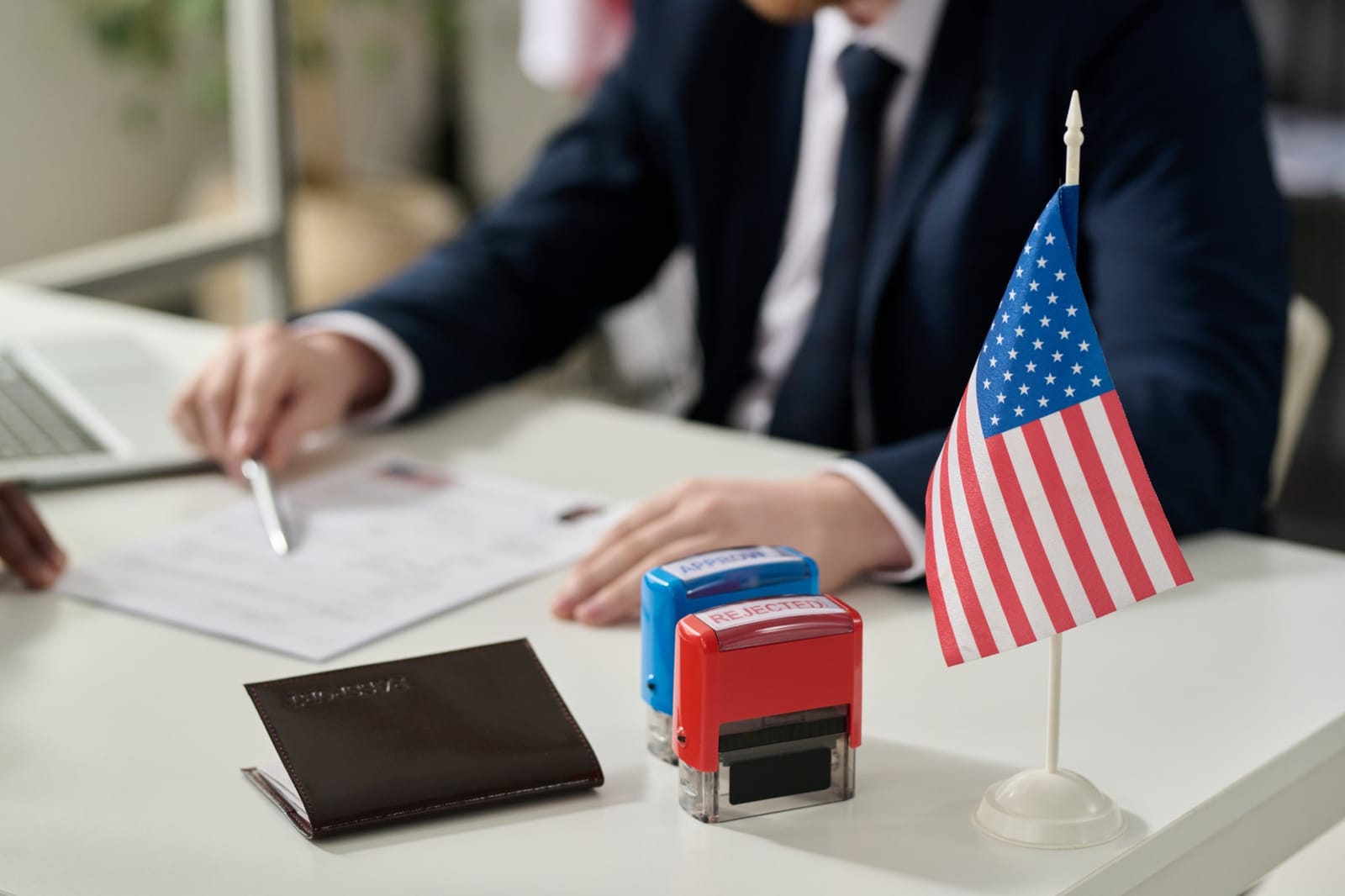 Carimbos de aprovado e rejeitado sobre mesa com passaporte e bandeira dos Estados Unidos
