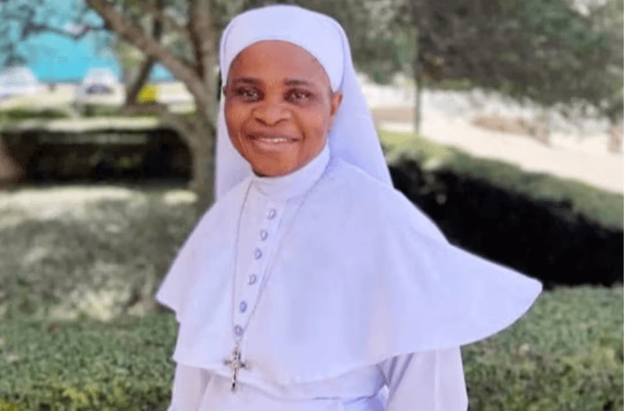 Irmã Leticia Ugboaja sorri em retrato ao ar livre, vestindo hábito branco e crucifixo