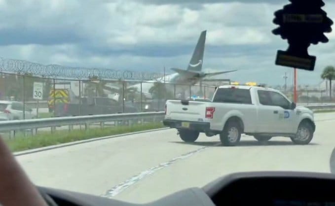 Avião cargueiro na pista de aeroporto, cercado por veículos de emergência