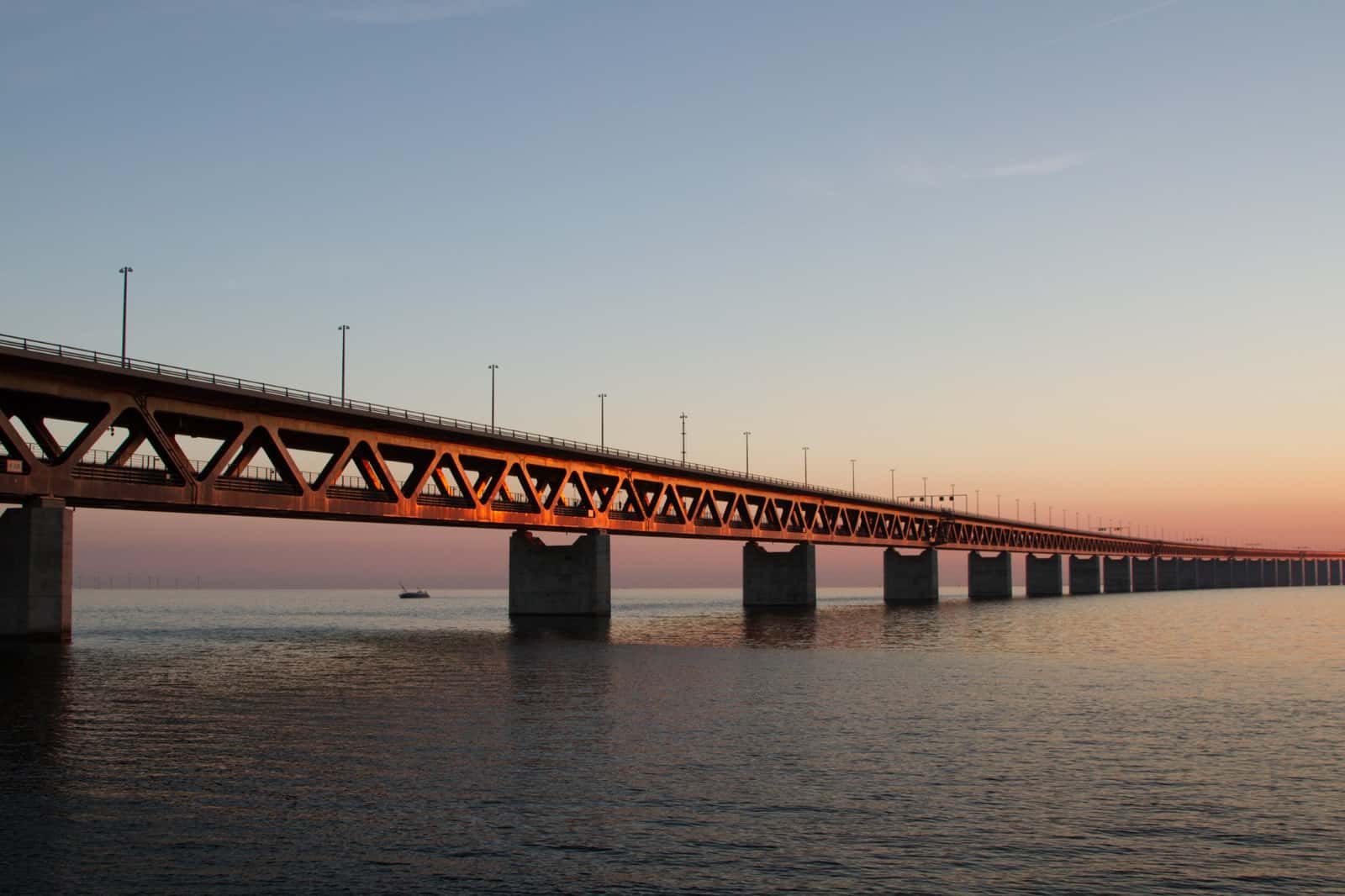 Ponte extensa sobre a água ao pôr do sol, vista de baixo