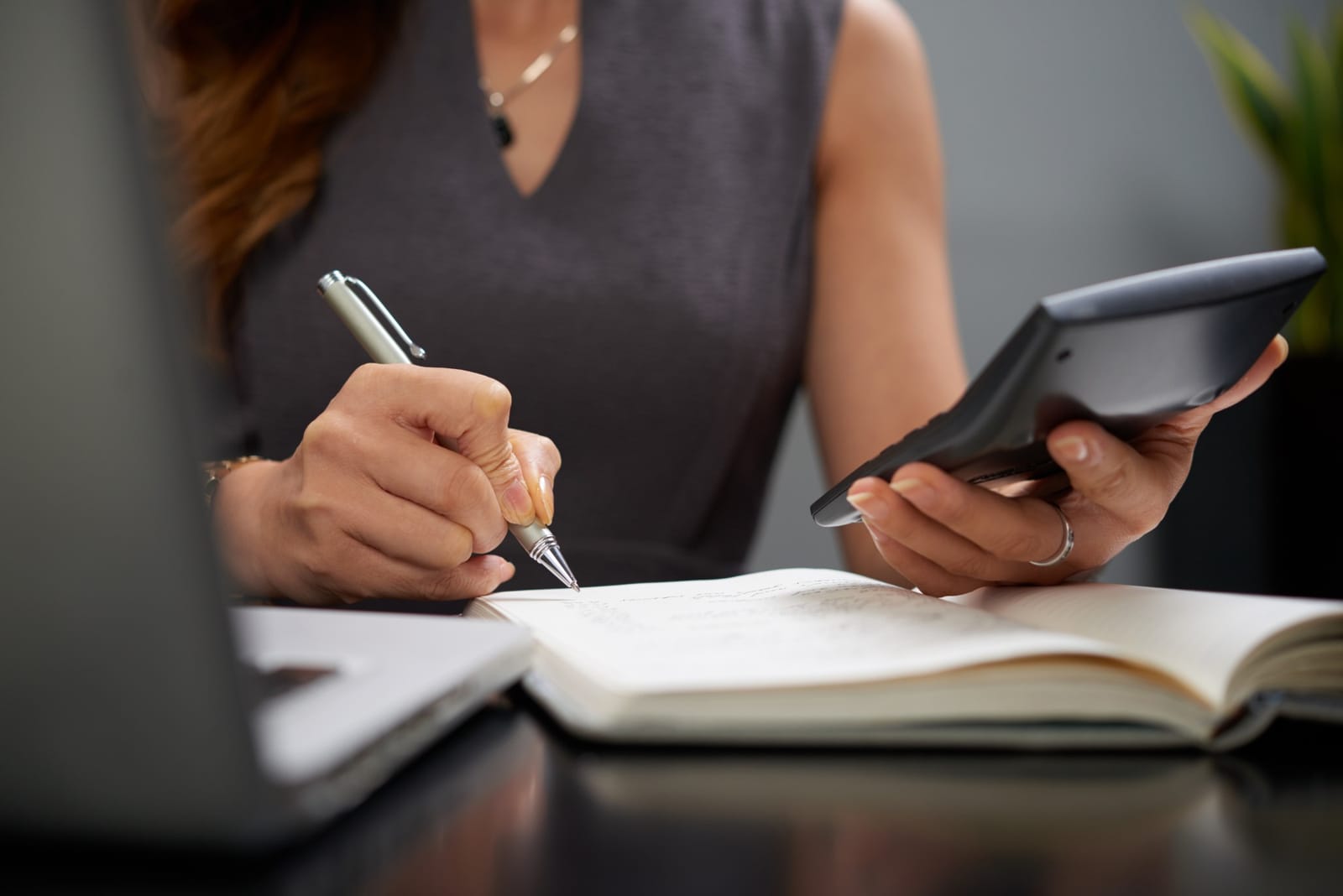 Mulher fazendo cálculo financeiro com calculadora e caderno de anotações