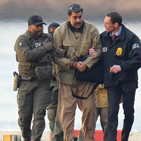 Homem de casaco bege, com as mãos algemadas, conduzido por agentes com coletes da DEA