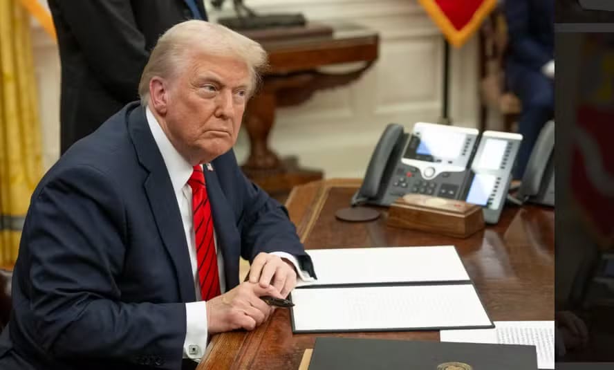 Presidente dos Estados Unidos sentado à mesa do Salão Oval, com documentos à frente