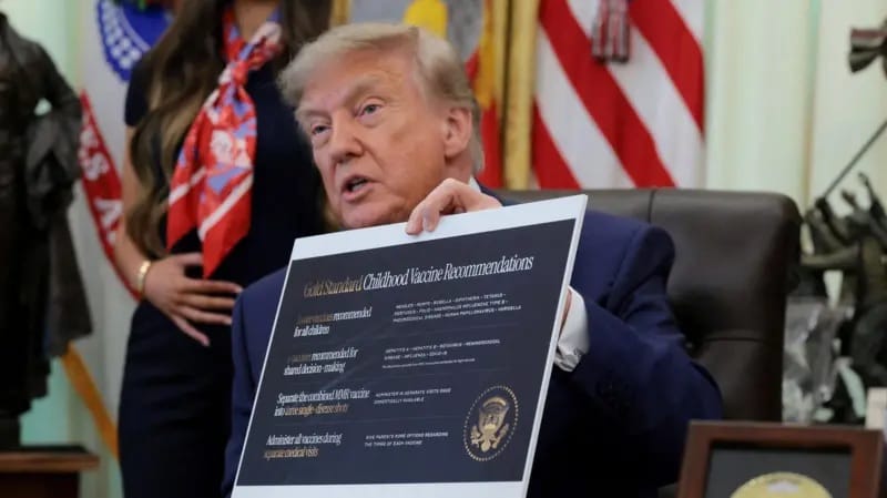 Presidente dos Estados Unidos, no Salão Oval, segura cartaz com o título Gold Standard Childhood Vaccine Recommendations diante de assessores