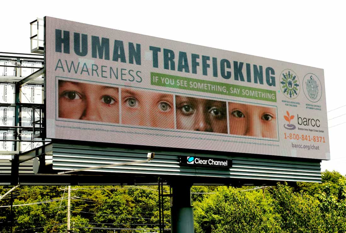 Outdoor digital sobre tráfico humano com a frase HUMAN TRAFFICKING AWARENESS e telefone de apoio, à beira de uma rodovia