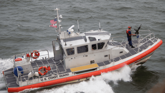 Embarcação de resposta laranja e branca da Guarda Costeira dos EUA navegando em mar aberto com tripulante a bordo