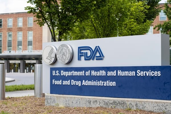Letreiro azul da Food and Drug Administration com os selos do Departamento de Saúde e da agência, em frente ao prédio da sede da FDA