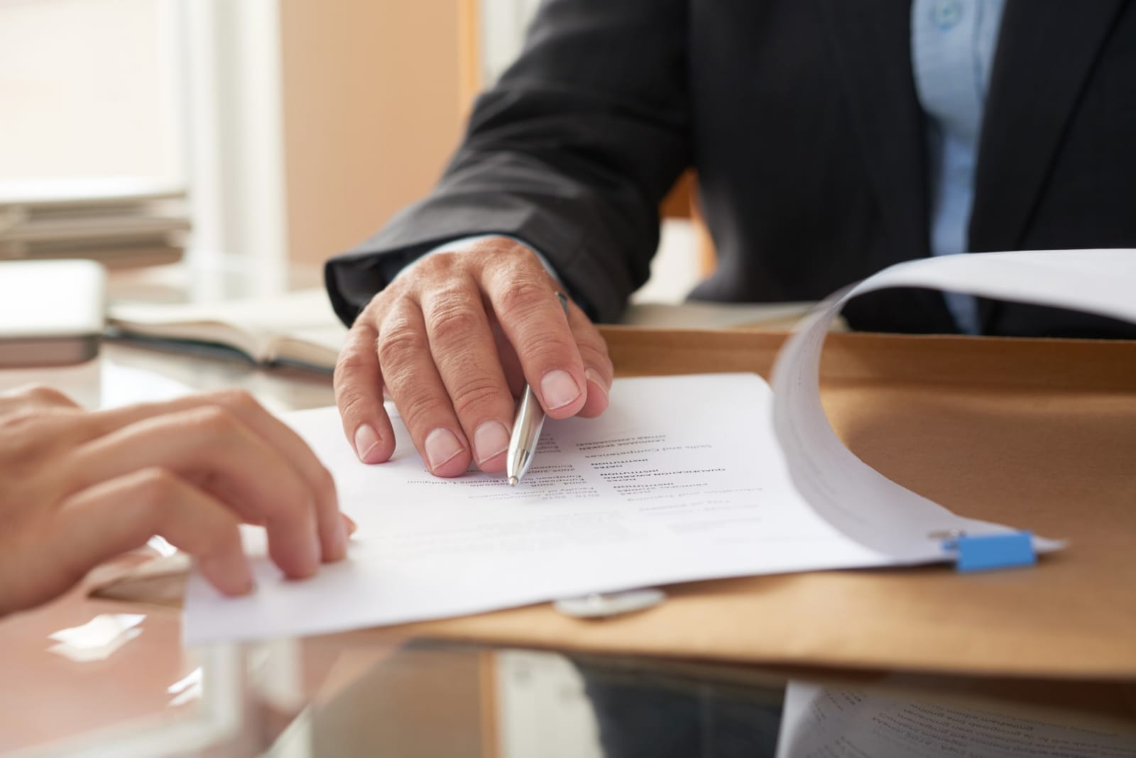 Duas pessoas assinando um contrato sobre uma mesa