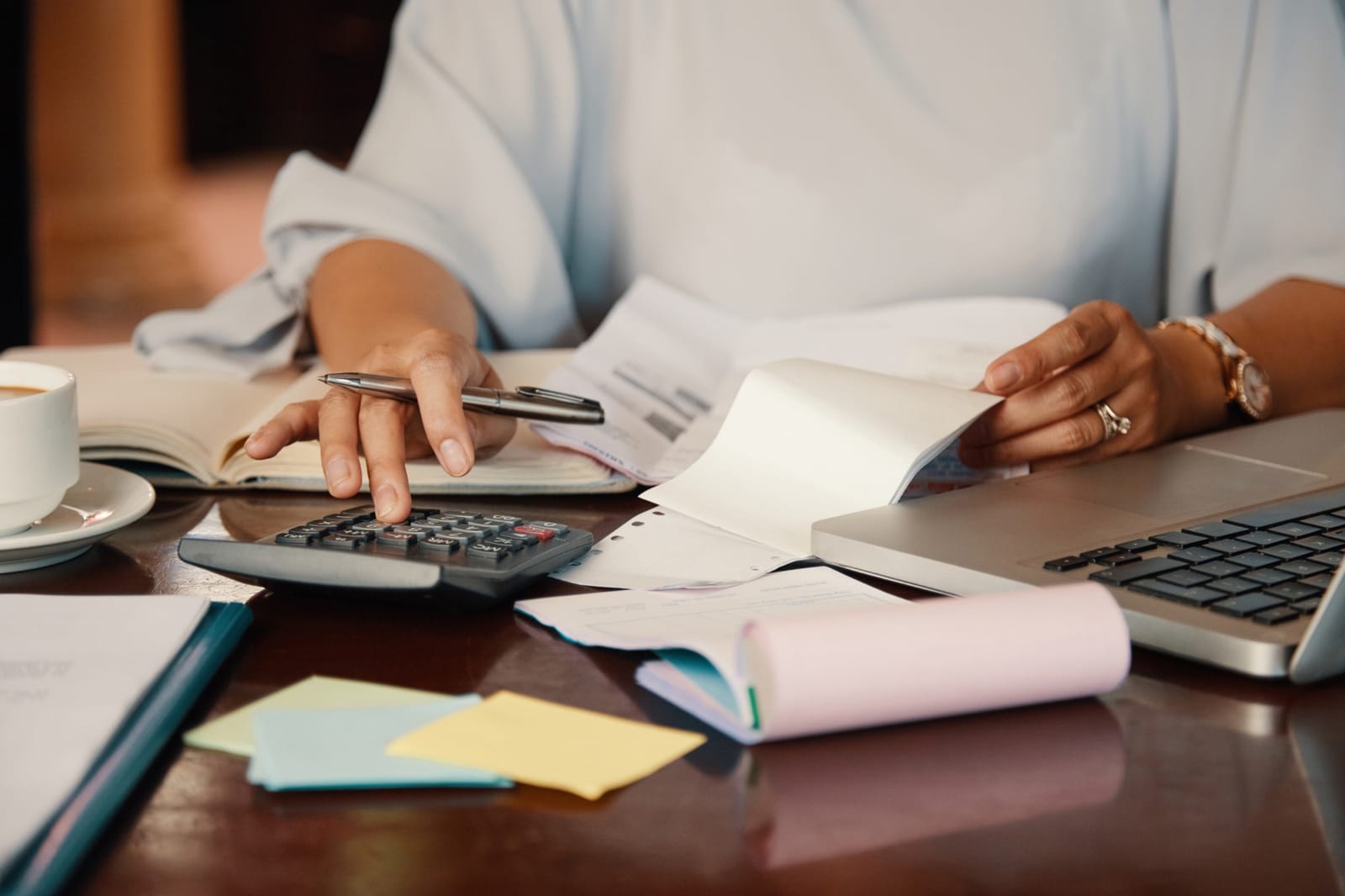Mulher fazendo cálculo financeiro com calculadora e documentos sobre a mesa