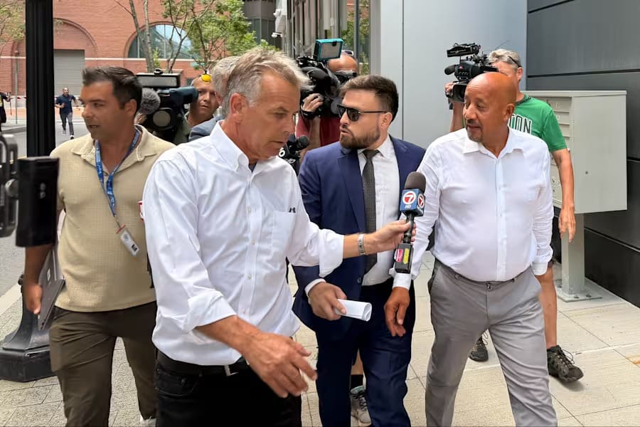 Homem de camisa branca deixa o tribunal federal de Boston cercado por cinegrafistas e por um repórter que estende um microfone