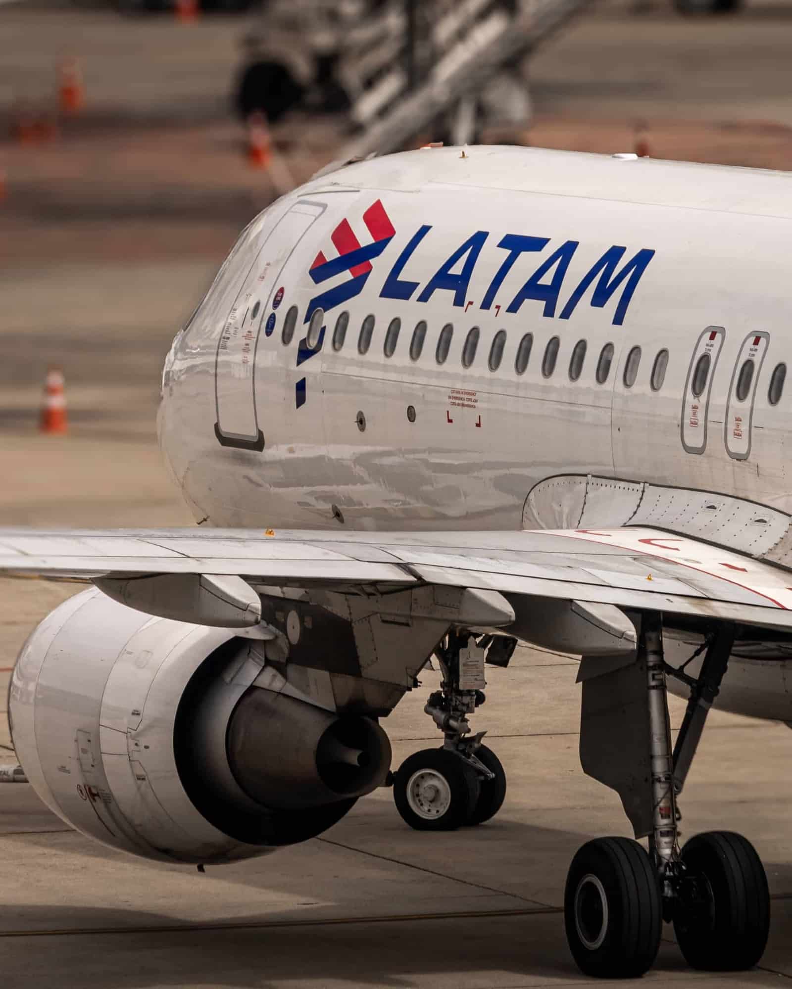Avião da Latam Airlines taxiando em pátio de aeroporto, visto de perto pela lateral da fuselagem com a marca da companhia