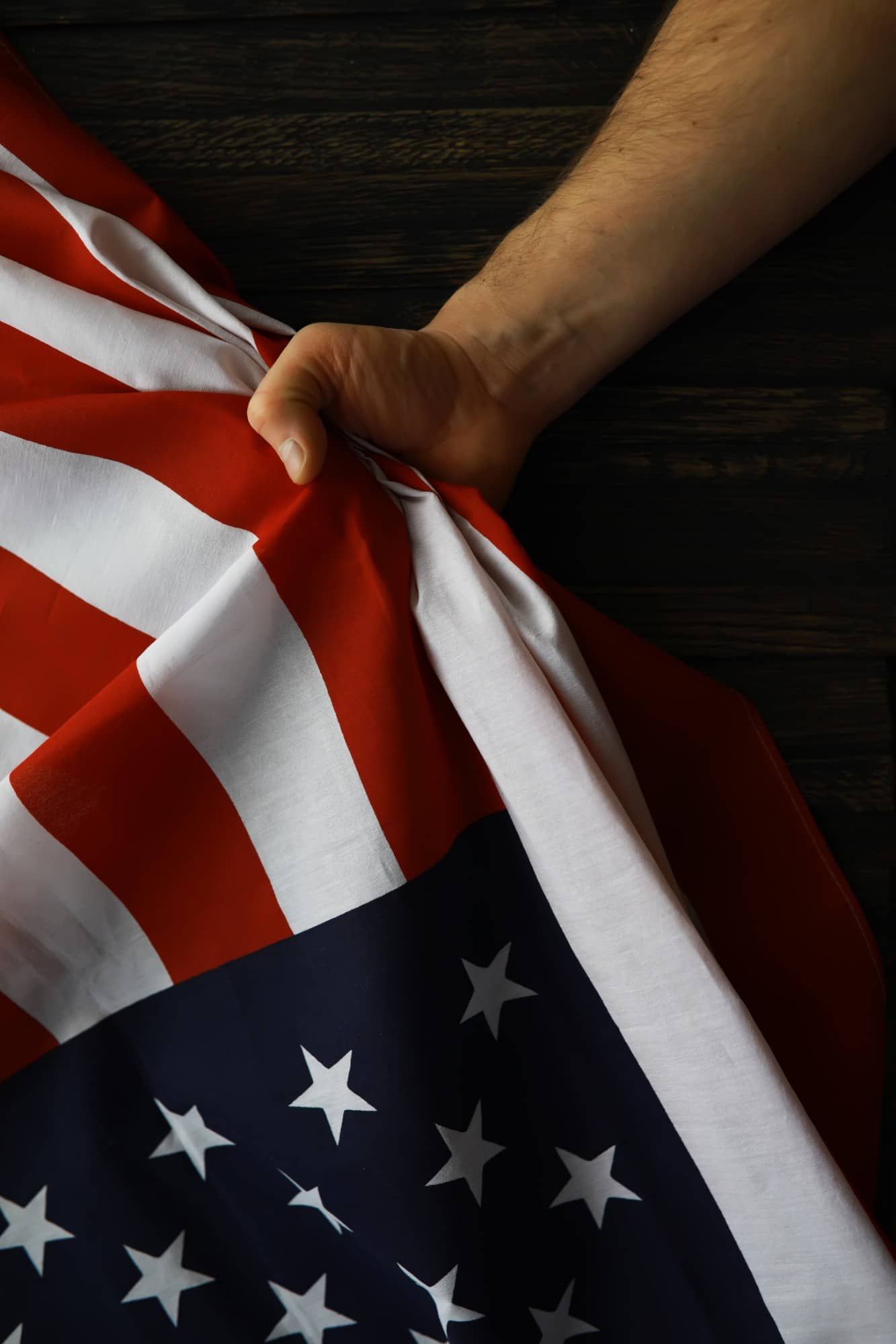 Mão segurando com força uma bandeira dos Estados Unidos enrolada