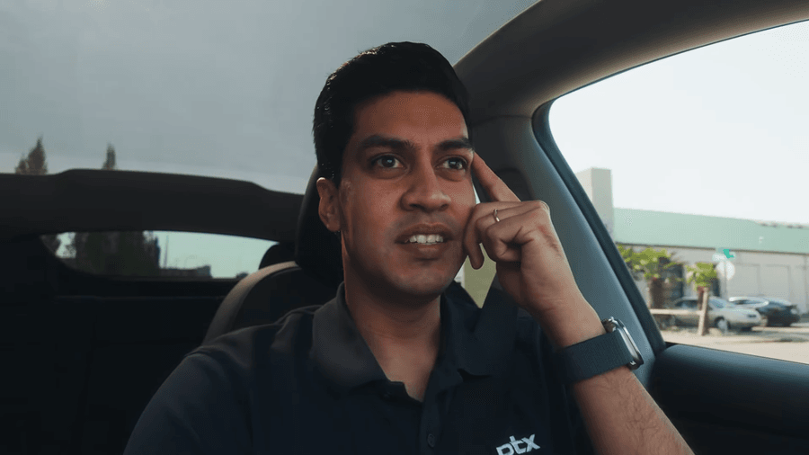 Darley Tomaz, de camisa polo escura com a marca ptx, gesticula apontando para a própria têmpora durante conversa gravada dentro de um carro