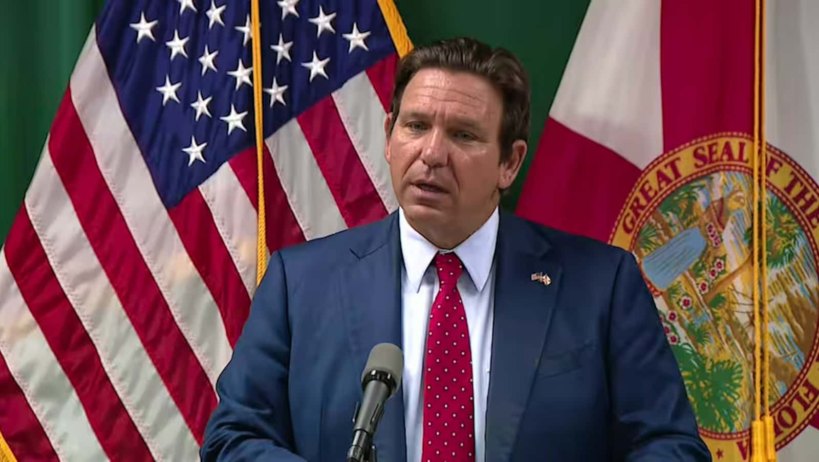 O governador da Flórida, Ron DeSantis, fala em um púlpito diante das bandeiras dos Estados Unidos e do estado da Flórida