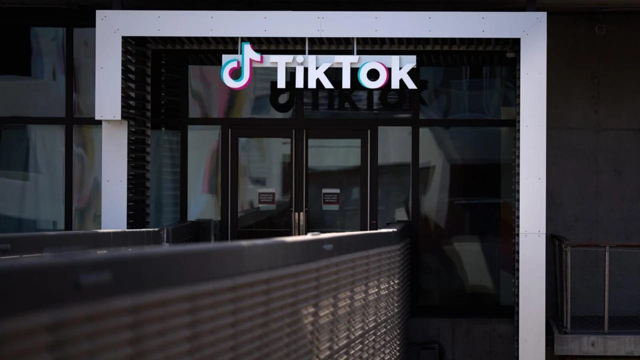 Fachada de um prédio com o logotipo do TikTok acima de portas de vidro, vista da rua