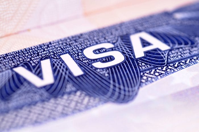 Detalhe em close de um visto americano, com a palavra VISA em destaque sobre o fundo azul do documento