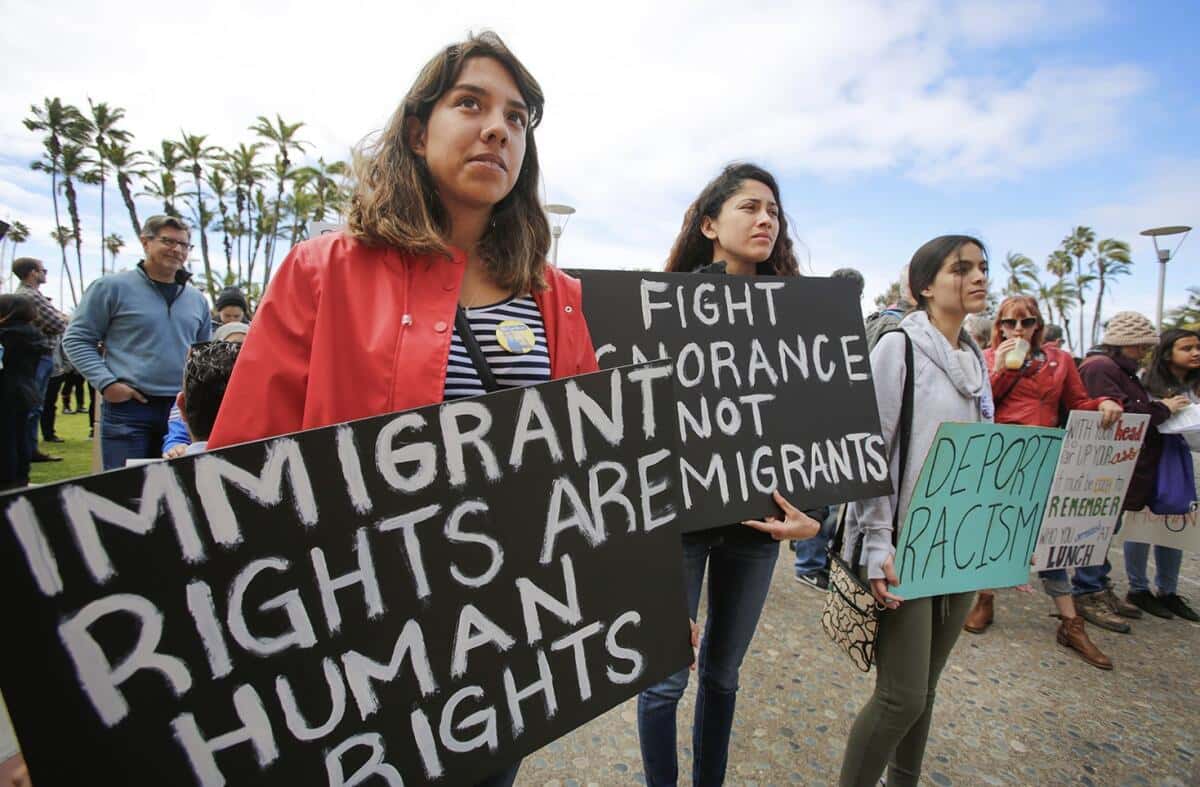 Manifestantes seguram cartazes em defesa dos direitos dos imigrantes
