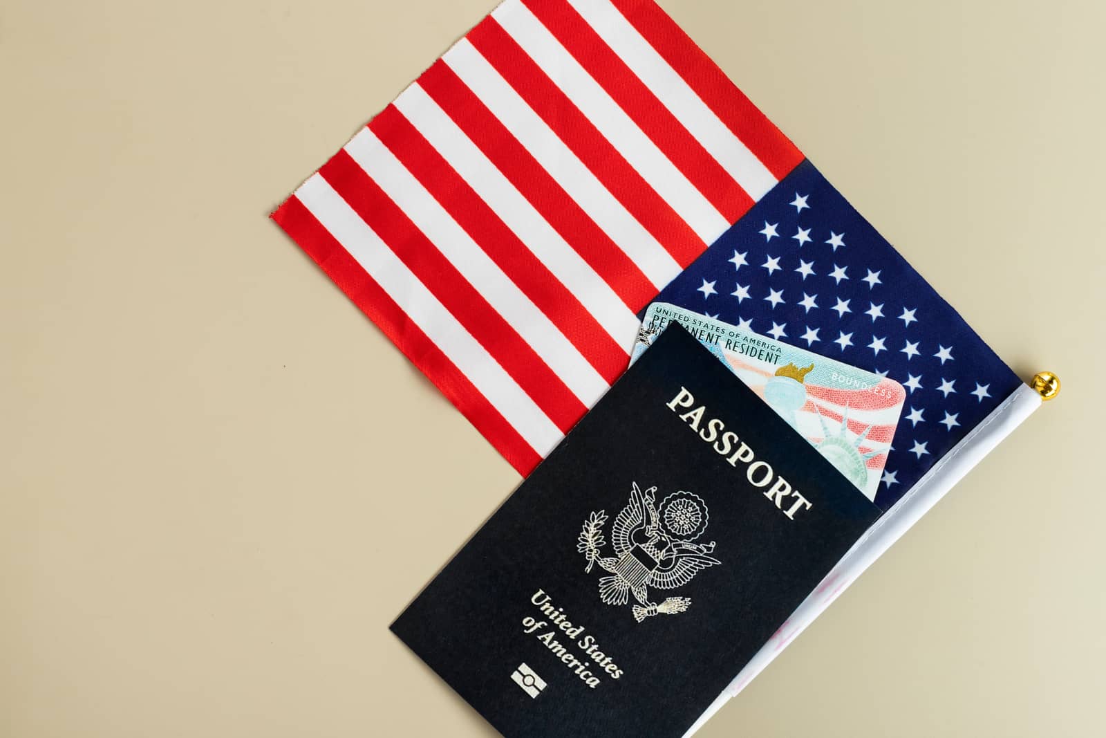 Passaporte dos Estados Unidos fechado sobre bandeira americana, com cartão de residente permanente aparecendo por baixo