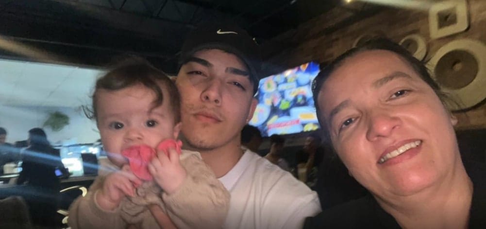 Elyézer Dias de Souza, de boné preto, aparece ao lado de uma criança de colo e da mãe, em foto de família