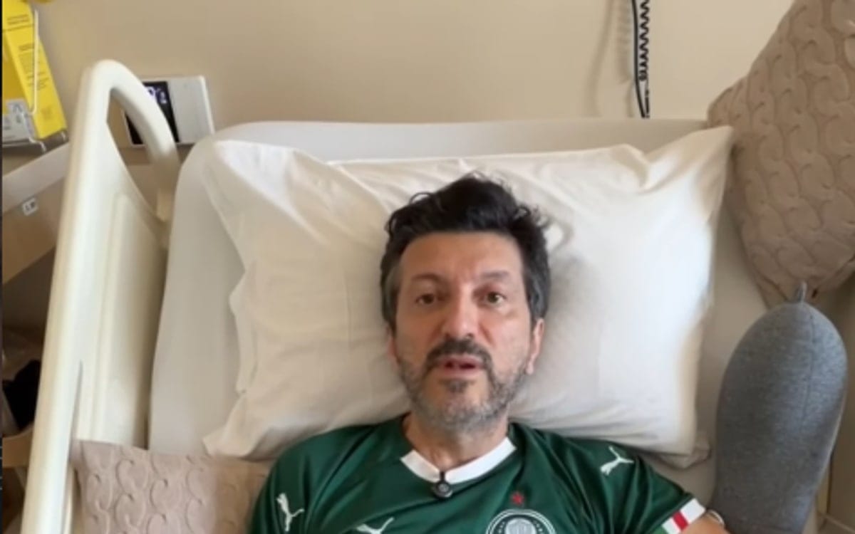 Lito Sousa, de camisa verde do Palmeiras, deitado em leito hospitalar, olhando para a câmera