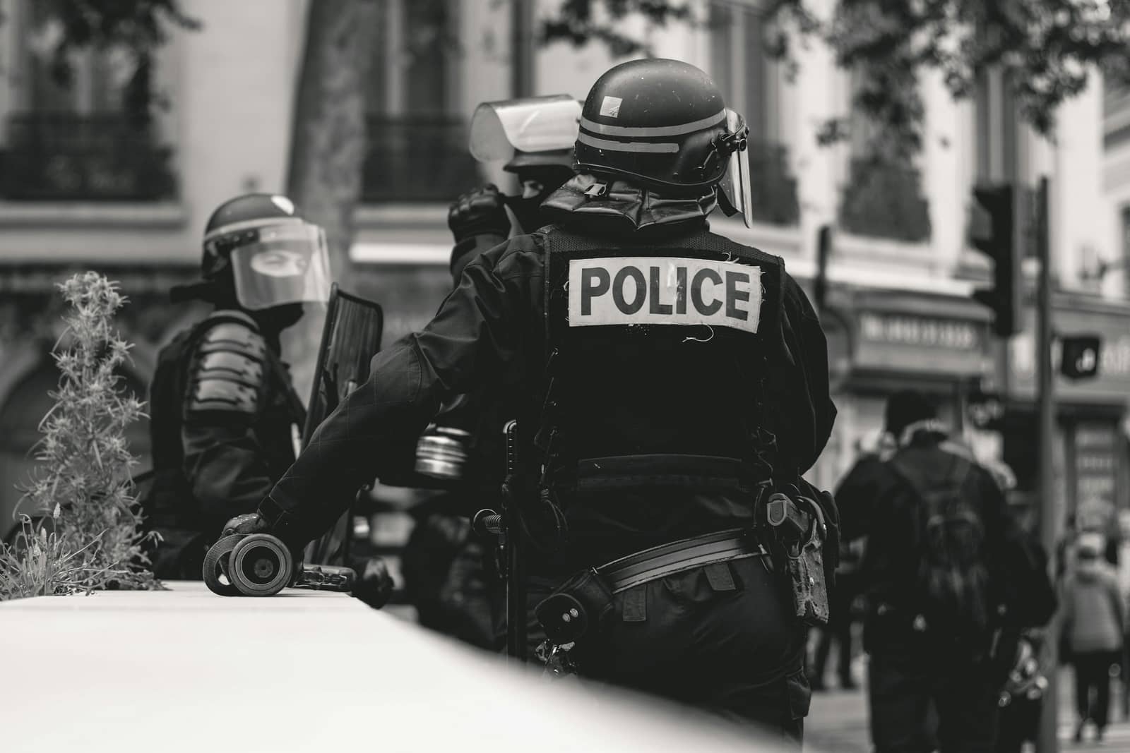 Agente de segurança fardado, visto de costas, em rua de cidade