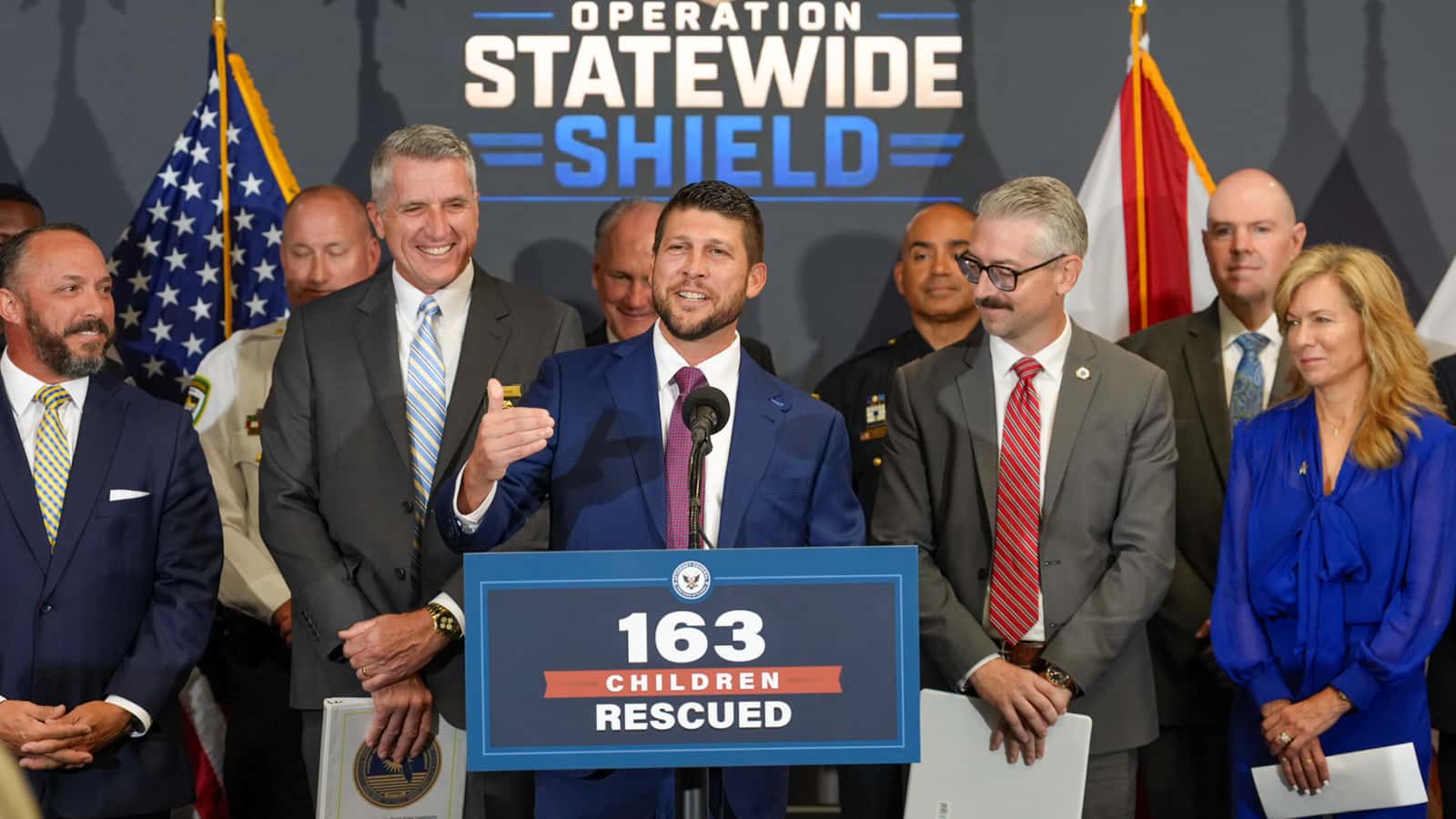 Coletiva de imprensa da Operação Statewide Shield, com painel indicando 163 crianças resgatadas