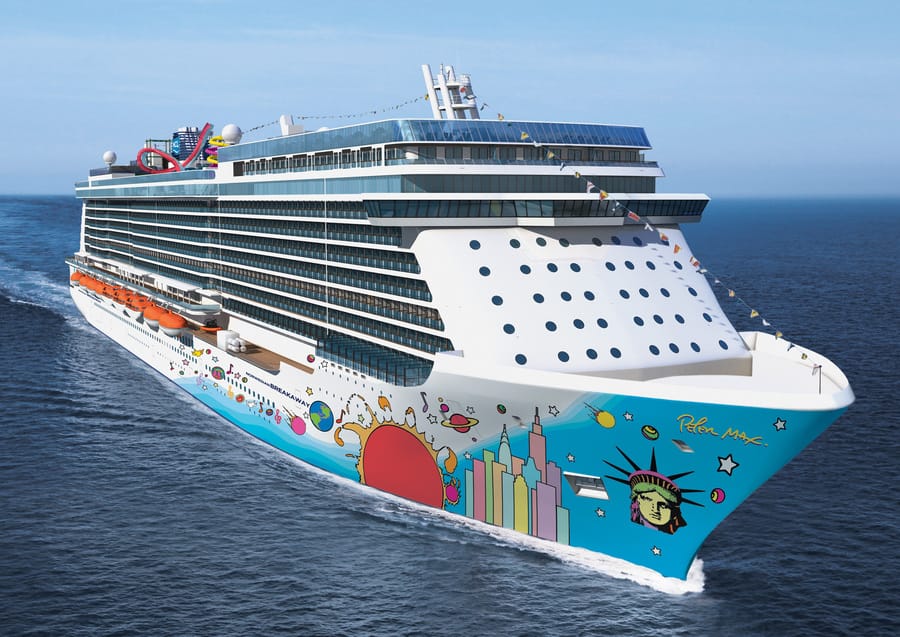 Grande navio de cruzeiro branco navegando em mar aberto, com pinturas coloridas no casco e uma estátua da Liberdade estilizada na proa