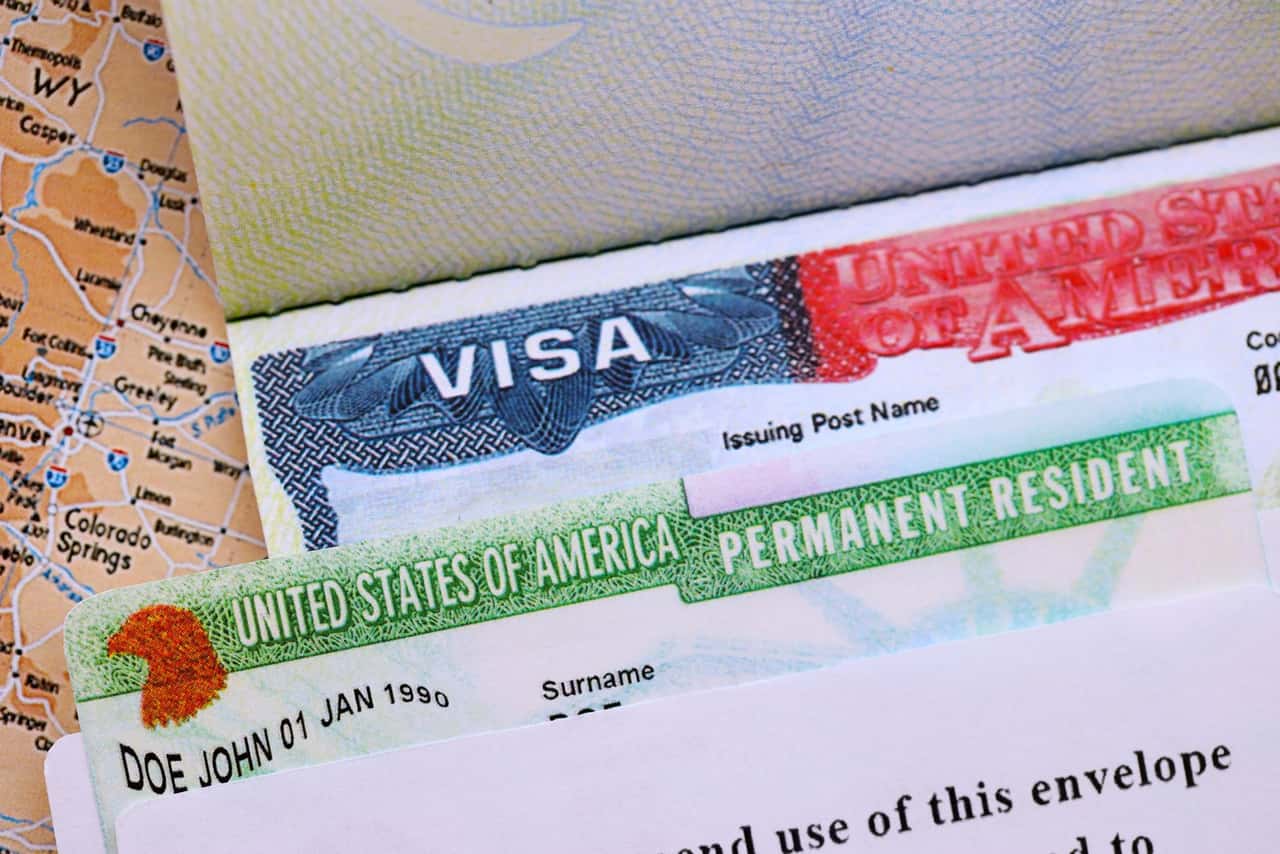 Detalhe de um visto americano e de um green card sobre um mapa, com as inscrições Visa e Permanent Resident