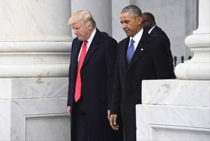 Donald Trump, de sobretudo escuro e gravata vermelha, e Barack Obama, de terno escuro, descem uma escadaria ao lado de colunas de pedra