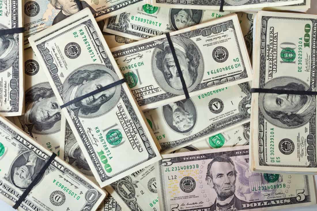 Pilhas de notas de dólar amarradas com elástico sobre mesa